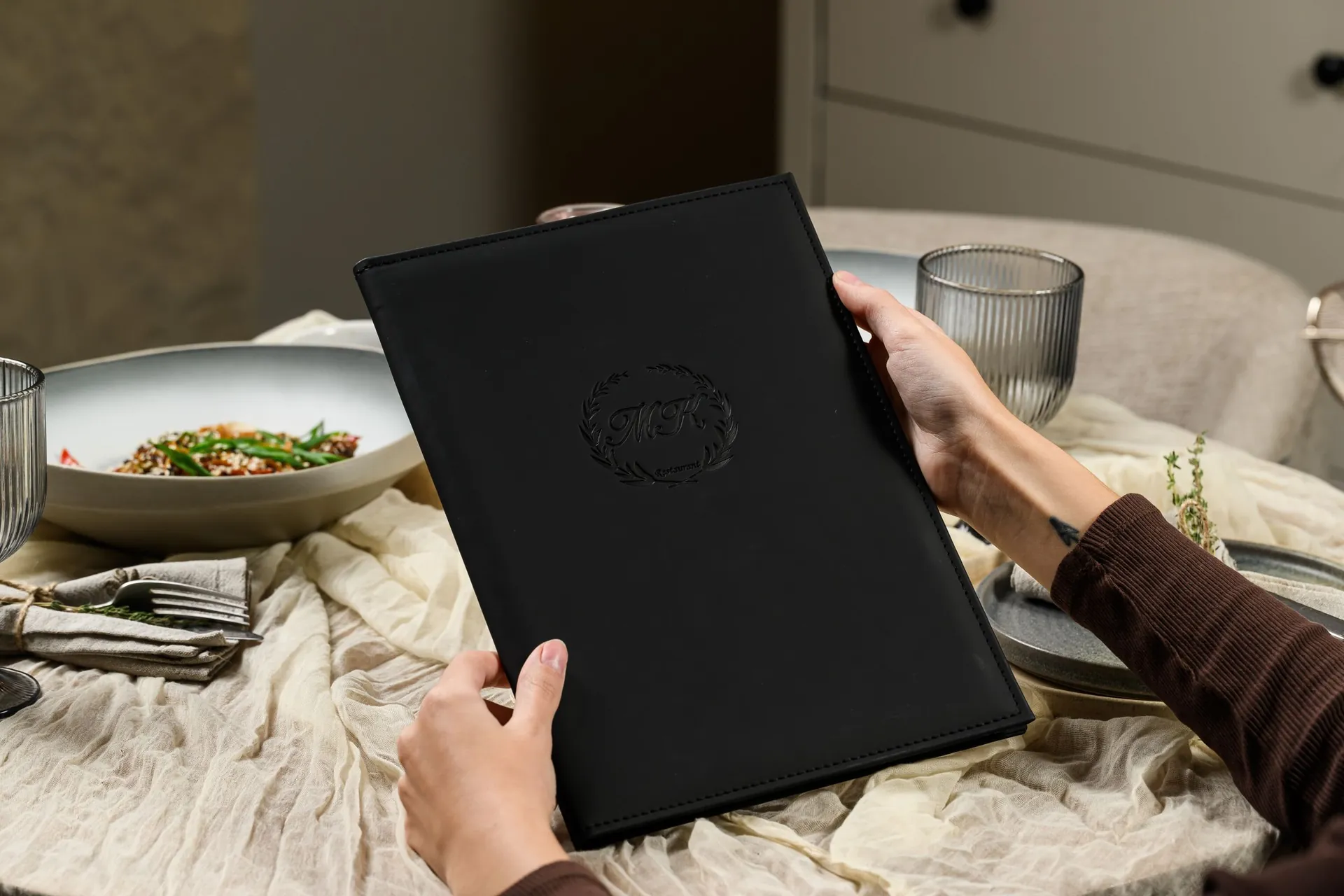 Leather menu cover with embossed venue logo on a set restaurant table